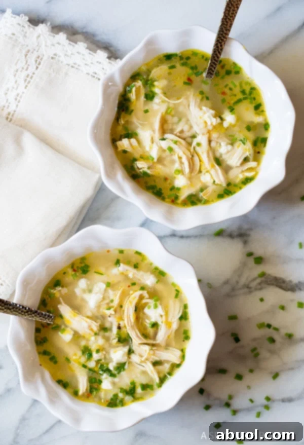 An inviting overhead shot of two bowls of Greek lemon chicken soup, garnished with fresh dill, ready to serve.