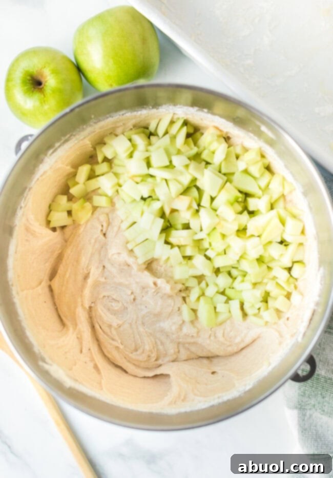 Cake batter with chopped apples in a mixing bowl. 