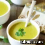 A small white bowl of creamy poblano pepper soup with a cilantro garnish.