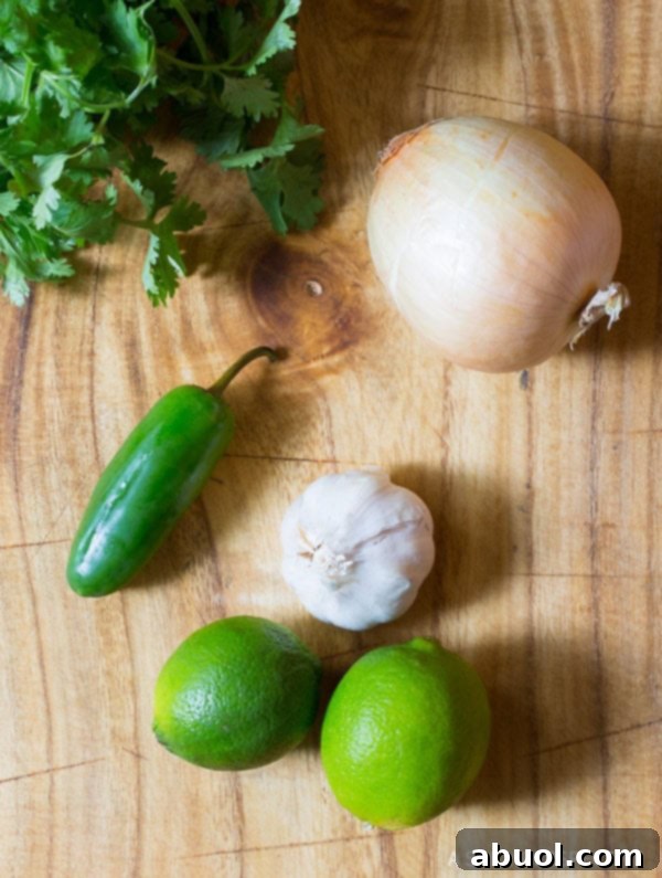 Fresh Ingredients for Flavorful Garlic Lime Chicken Skillet A flat lay photograph showcasing all the fresh and essential ingredients required for making the Garlic Lime Chicken: chicken breasts, fresh limes, garlic cloves, onion, jalapeño, cilantro, and various spices.
