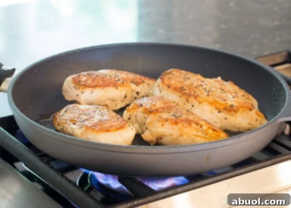 Cooking Poultry for Garlic Lime Skillet Chicken A boneless, skinless chicken breast being pan-seared in a hot skillet with olive oil on a stove, achieving a golden-brown crust.
