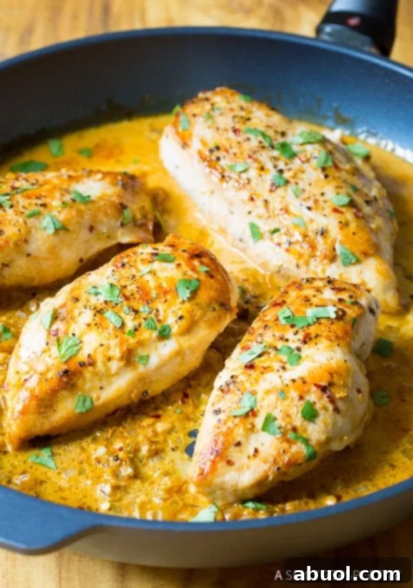 Garlic Lime Chicken Skillet Ready to Serve Four perfectly cooked, large chicken breasts arranged neatly in a skillet, generously coated with a luscious, bright yellow garlic-lime sauce, garnished with fresh herbs.