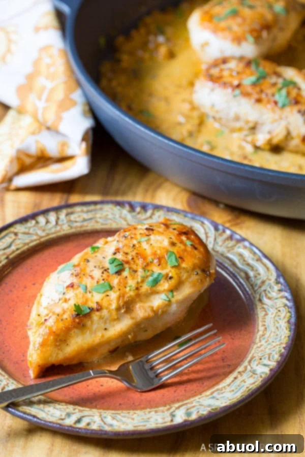 Zesty Garlic Lime Chicken 2 A beautifully plated serving of Garlic Lime Chicken on a white plate, with the skillet of remaining chicken and sauce blurred in the background, highlighting the ready-to-eat meal.