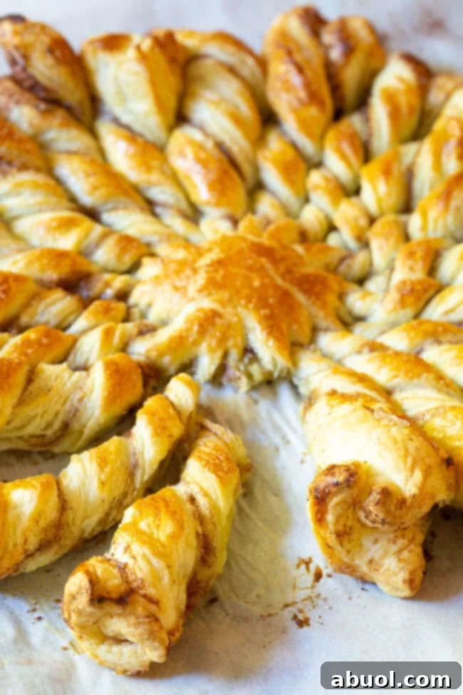 Close-up shot of a golden-brown puff pastry pull-apart bread, showing the individual twisted strands and a hint of the sweet filling.
