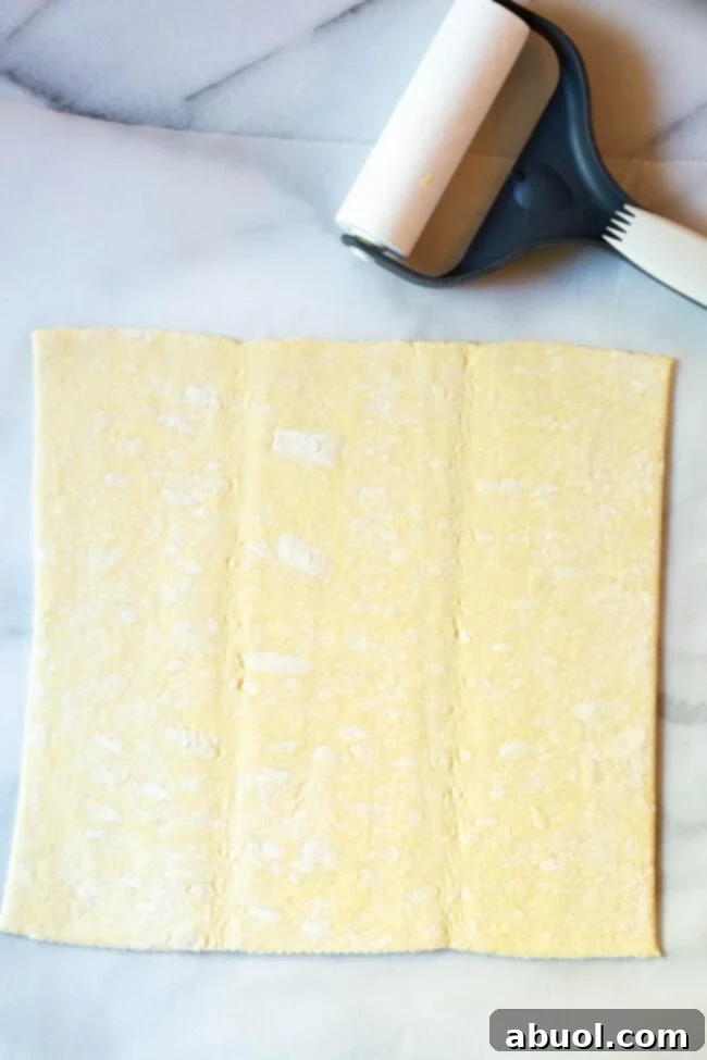 Two sheets of thawed puff pastry laid out on parchment paper, ready for filling application.