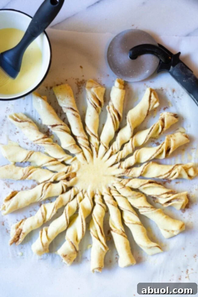 Puff pastry strips twisted into ropes and arranged in a sunburst pattern on a baking sheet, ready for the oven.