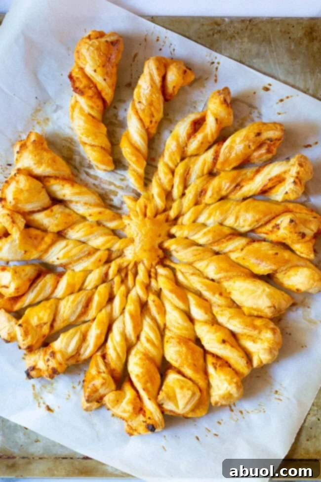 Crispy golden Sunburst Pull Apart Bread on a white baking sheet, viewed from overhead, with a perfect sun-like shape.