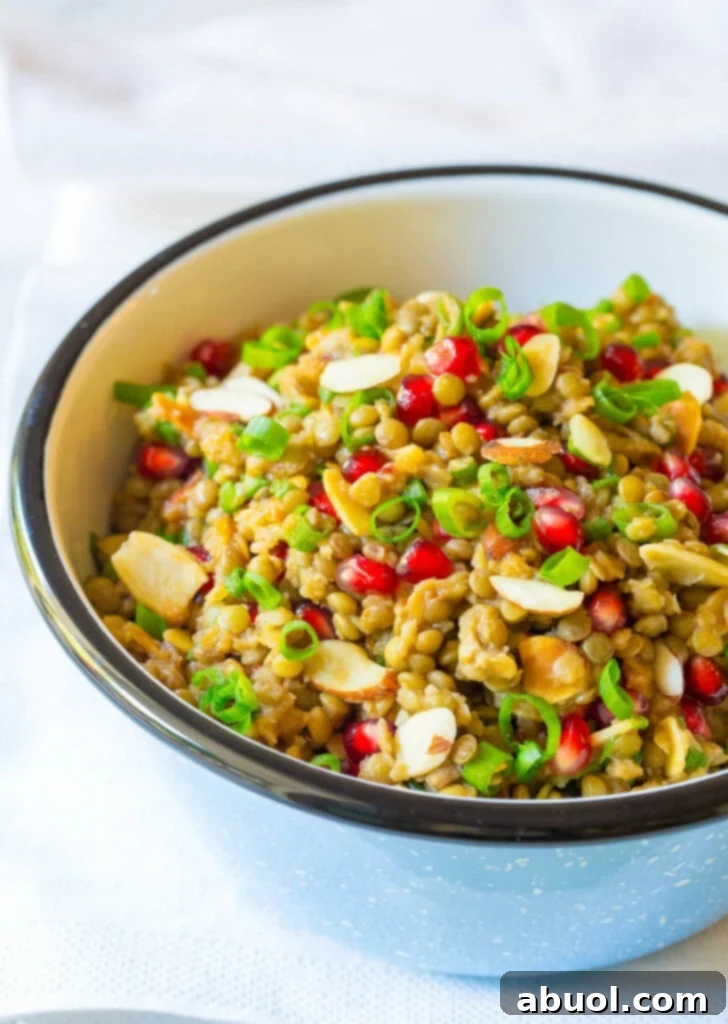 Lentil salad with pomegranate, almonds and scallions in a serving bowl. A vibrant and healthy addition to any meal.