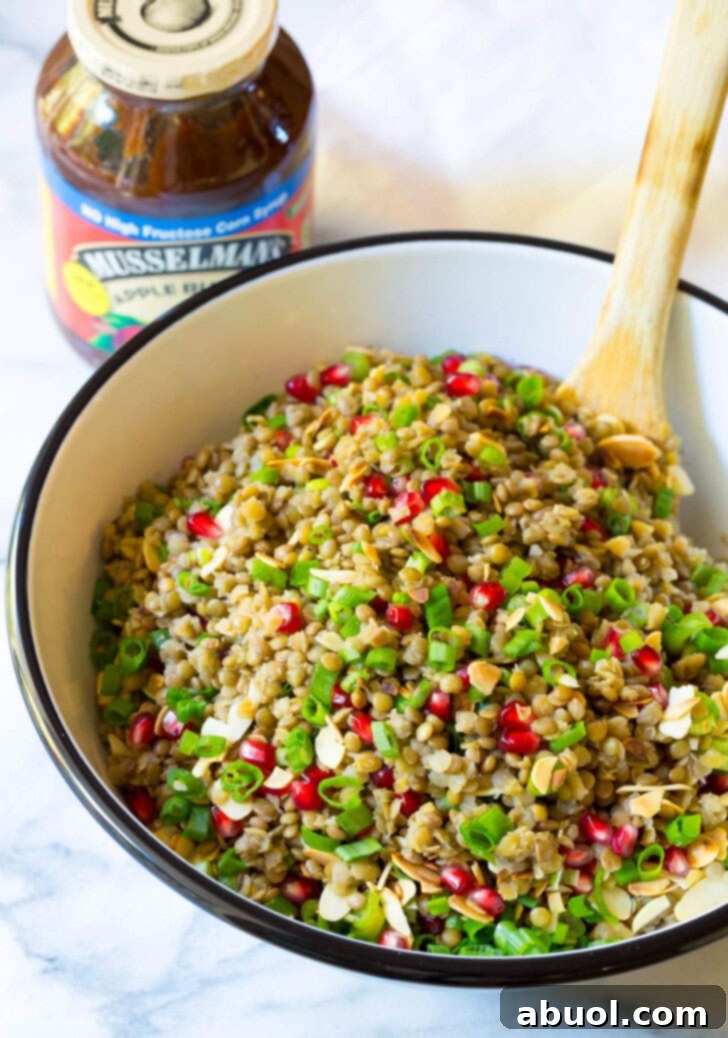 Healthy Lentil Salad with Apple Cider Vinaigrette in a large serving bowl with a wooden spoon. Ready to be served.