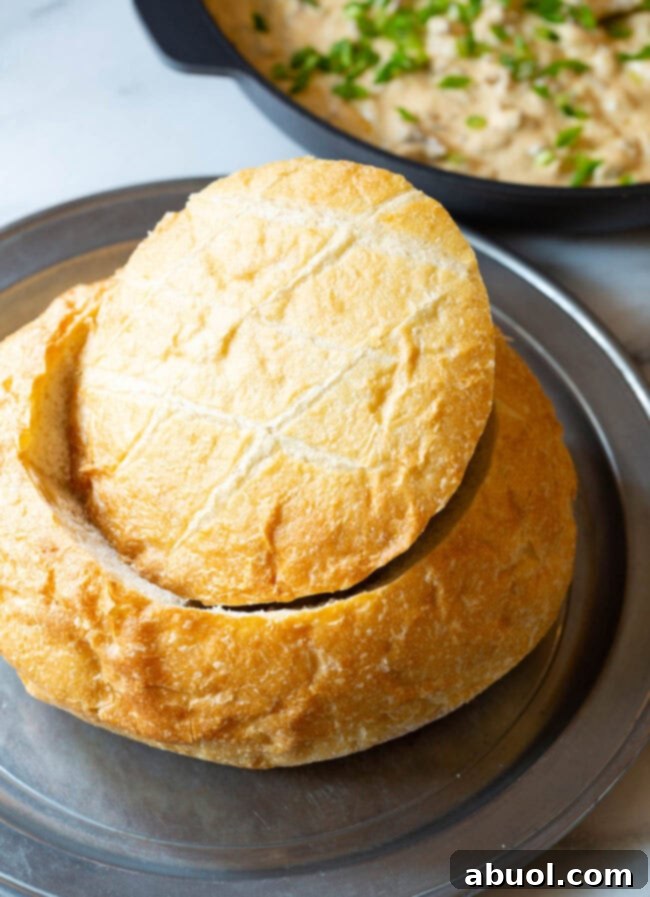 A bread bowl with the top piece cut out on a plate.