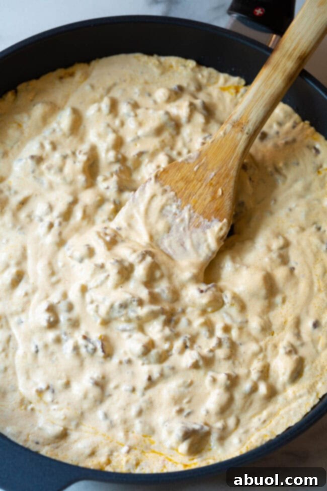 Sausage cheese dip in a skillet with a wood spoon.