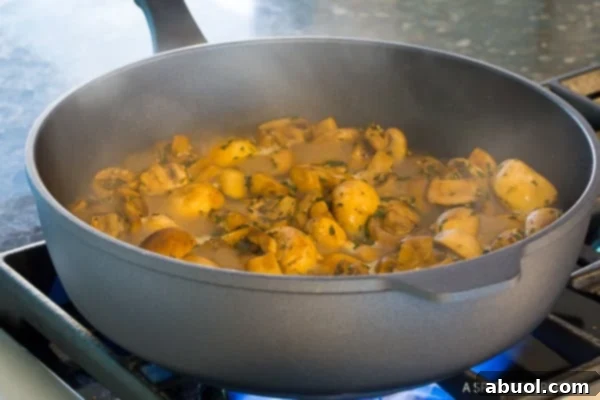 Sautéed mushrooms in a pan after seasonings have been added, showing their rich color and fragrant herbs.