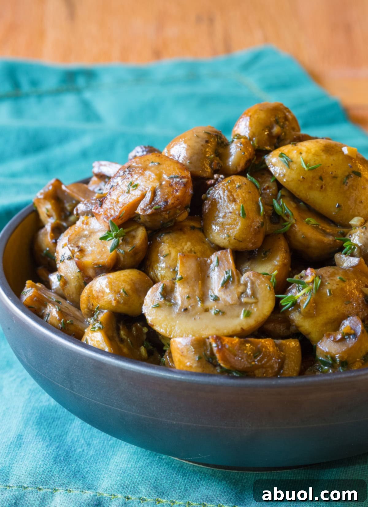 A elegant serving bowl brimming with perfectly sautéed mushrooms, artfully garnished with fresh thyme sprigs, showcasing their rich, inviting appeal.
