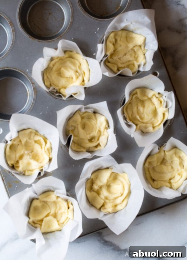Cheater Kouign Amann dough pressed into a muffin tin, ready for baking, showcasing its raw layered form.