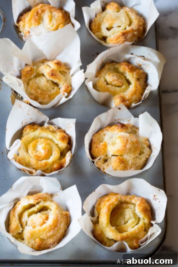 Baked Kouign Amann pastries still in their muffin tin, glistening with caramelized sugar.