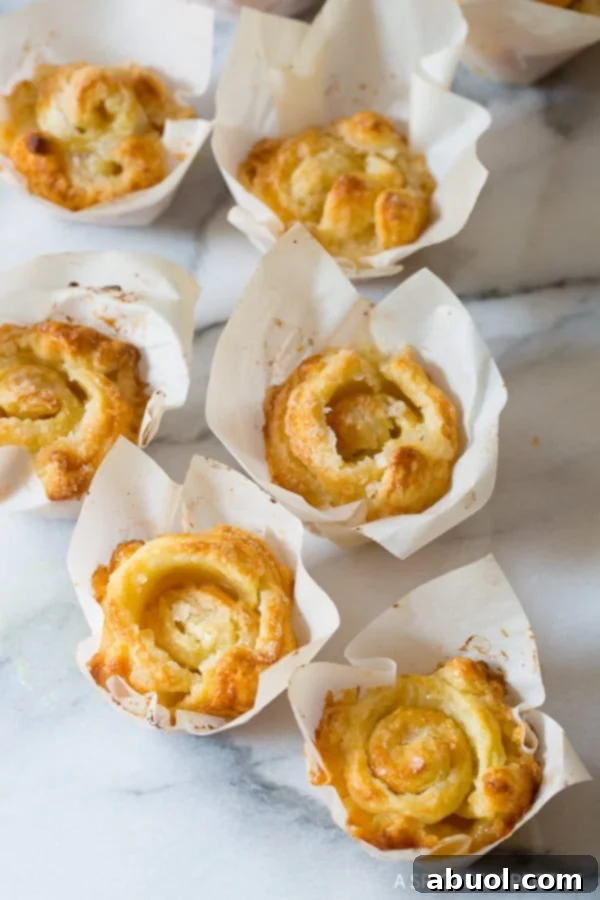 Freshly baked Kouign Amann pastries arranged in parchment squares on a kitchen counter, ready to be enjoyed.