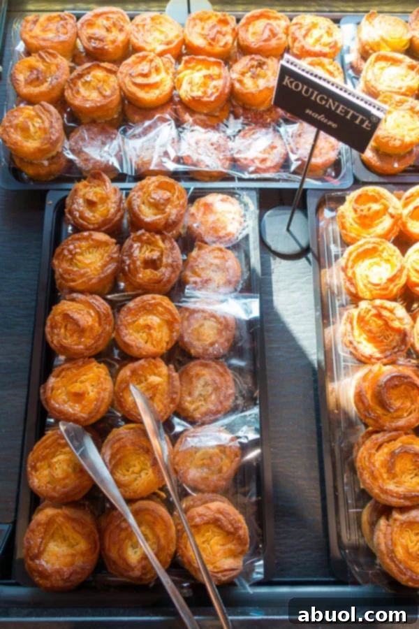 Individual Kouignettes, smaller versions of Kouign Amann, displayed in a charming French pastry shop.