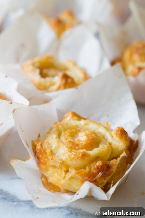 A close-up shot of a single, freshly baked 'cheater' Kouign Amann pastry, highlighting its flaky layers and caramelized sugar.