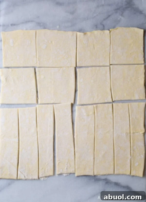 Puff pastry sheets expertly cut into squares and strips, laid out on a clean counter, ready for assembly.