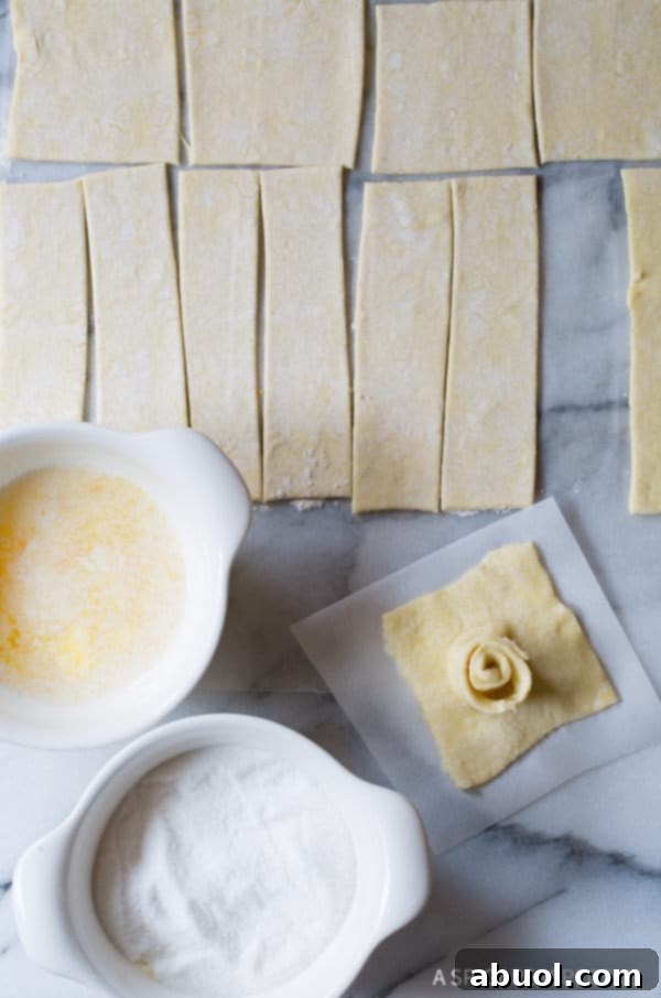 An overhead shot illustrating the assembly process of Kouign Amann, with spirals placed on top of squares.
