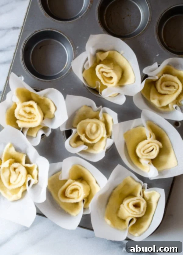 Assembled Kouign Amann pastries nestled in a muffin tin, before being baked to golden perfection.