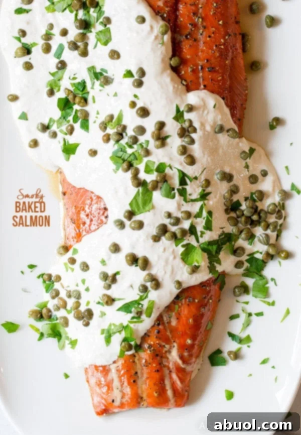 Baked salmon covered in horseradish sauce, capers and herbs, presented beautifully on a platter.