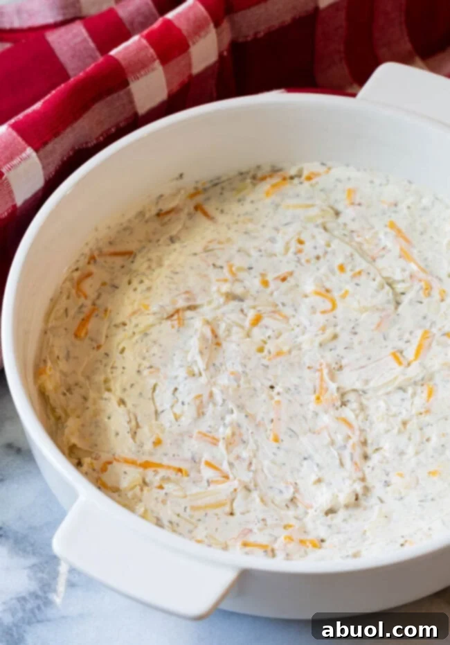 A pristine white baking dish showcasing the smooth, even layer of cream cheese mixture spread across its bottom, ready for the next culinary steps.