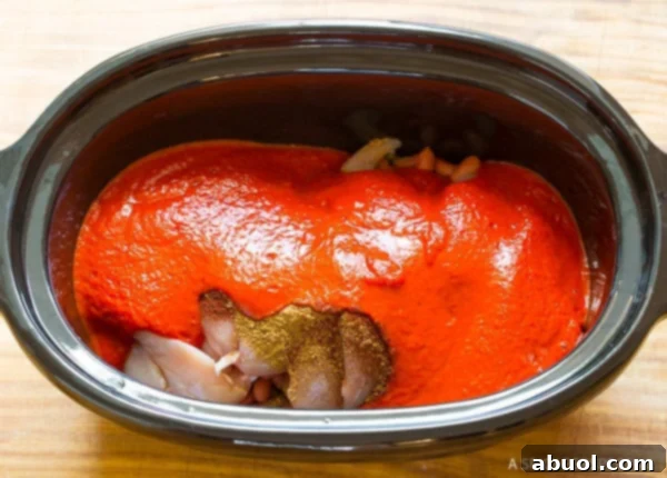 Roasted Red Pepper Crockpot Chicken Chili 6 Slow cooker with raw chicken breasts covered in pureed red pepper sauce.