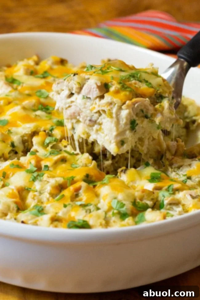 A delicious King Ranch Chicken Casserole in a baking dish, with a metal spatula serving a creamy, cheesy slice, showcasing its layers of chicken, tortillas, and melted cheese, ready to be enjoyed.