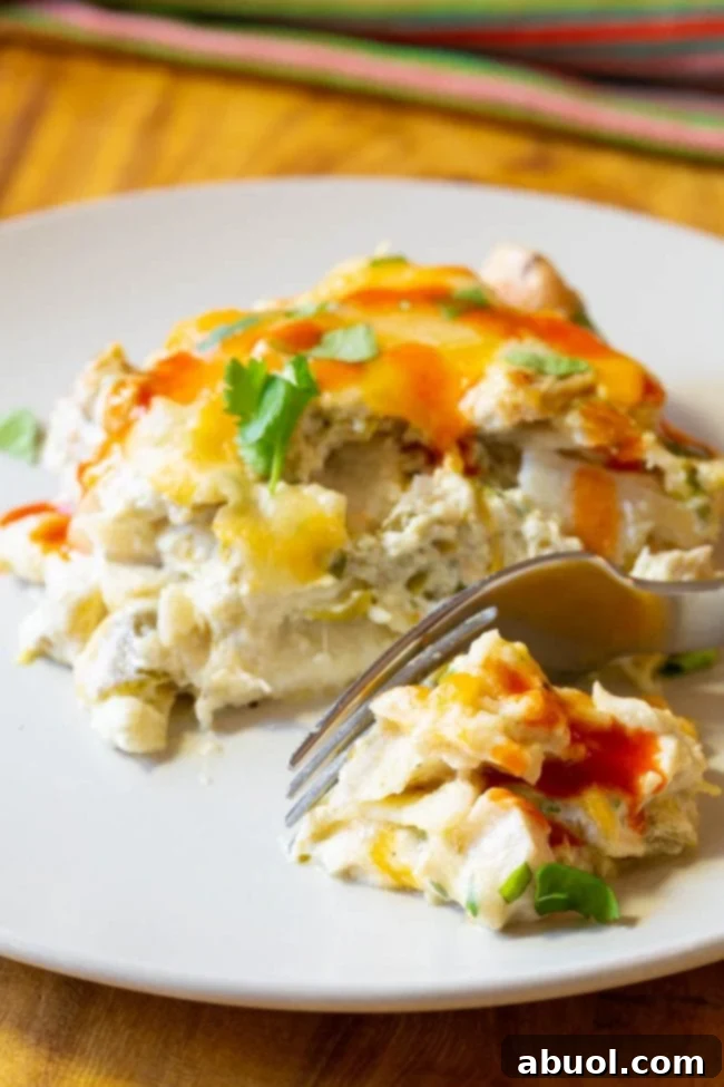 A single serving of King Ranch Chicken Casserole drizzled with Cholula hot sauce, with a fork ready to scoop a bite.