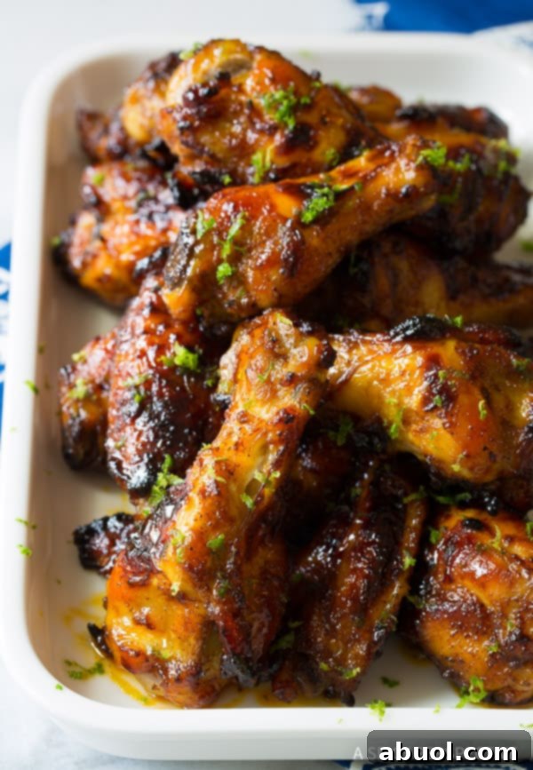 Baked Chili Lime Chicken Wings Chili Wings - White baking dish loaded with chili lime baked chicken wings, garnished with fresh lime zest and cilantro.