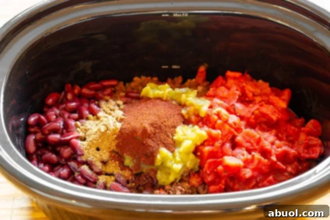 The initial browning of ground beef and chorizo with chopped onions, bell pepper, and garlic in a sauté pan before transferring to the slow cooker.