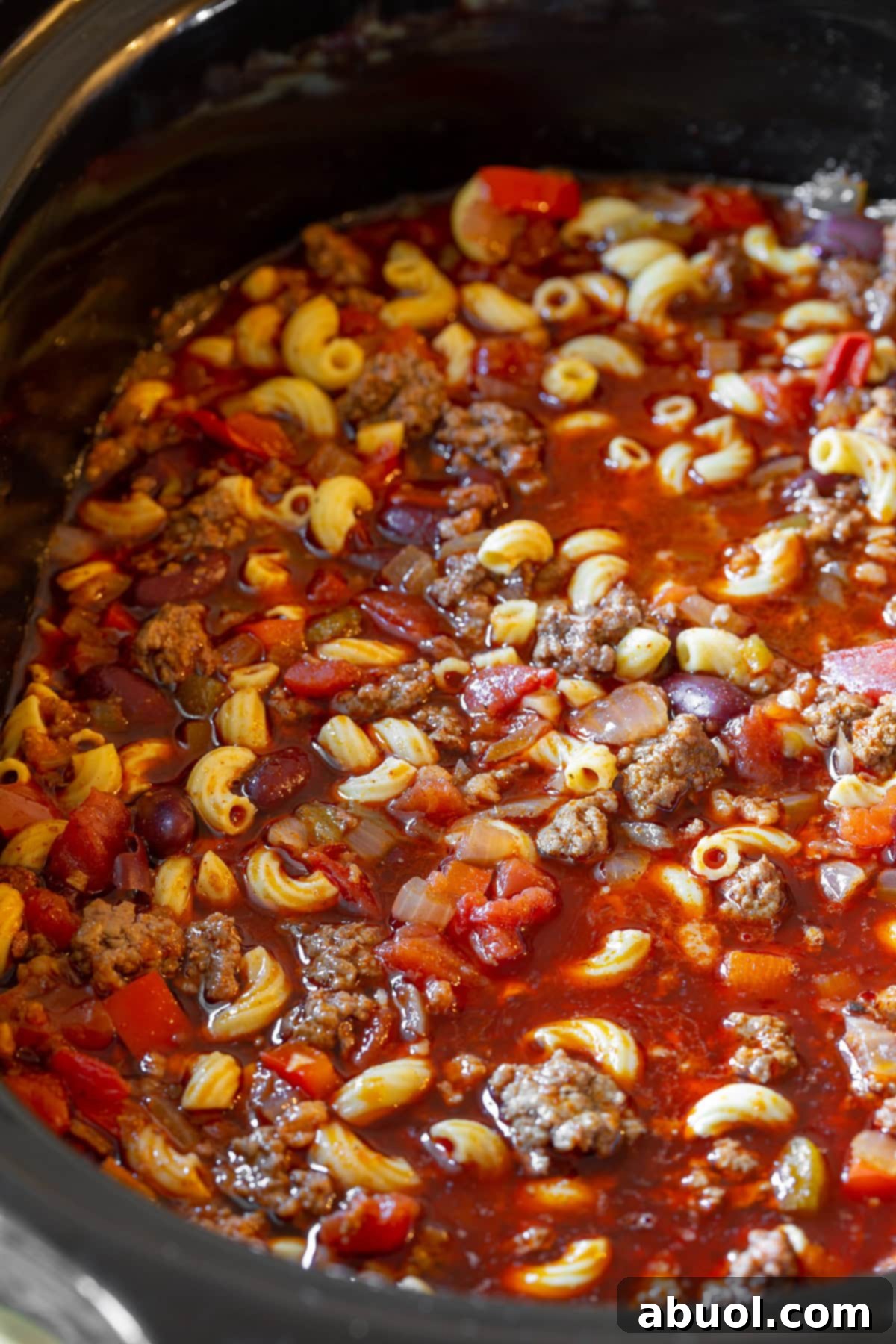 A vibrant close-up of all the chili mac ingredients simmering together in the slow cooker, before the final addition of cheese and cilantro.