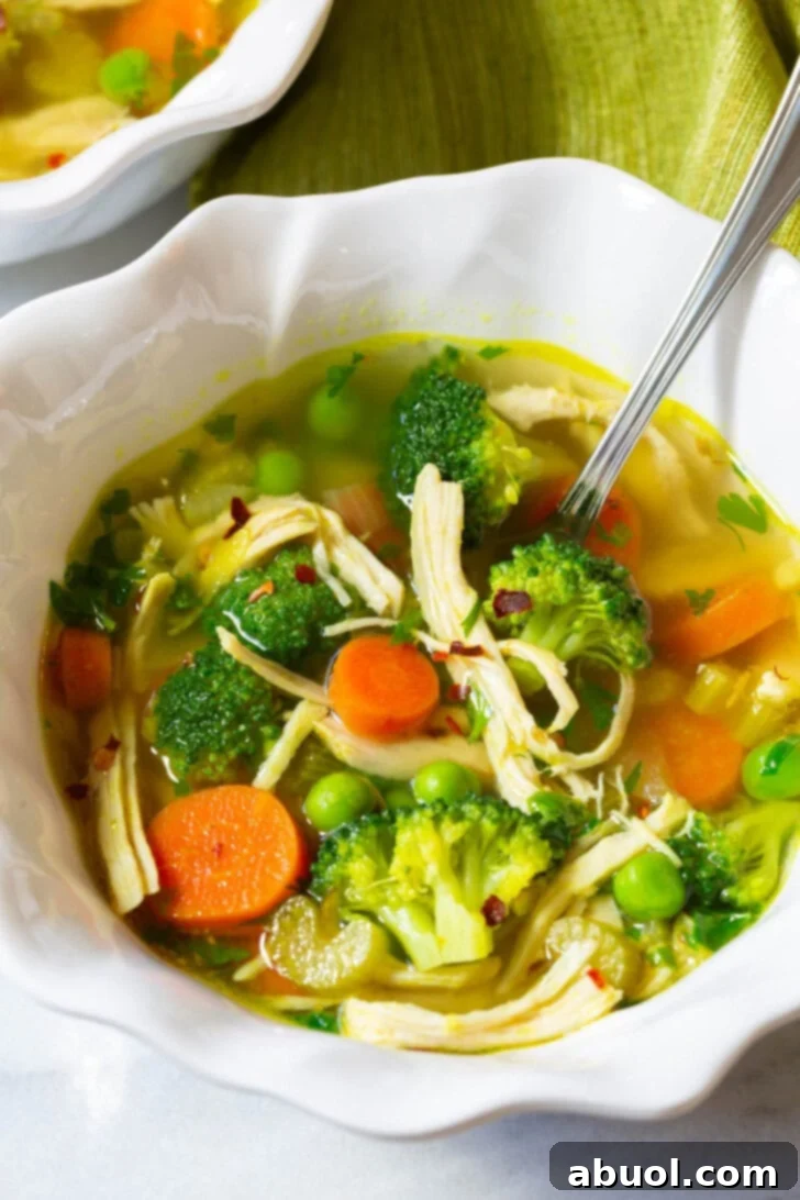 A single bowl of vibrant Chicken Detox Soup, garnished with fresh herbs, and a spoon resting inside, ready to be enjoyed.