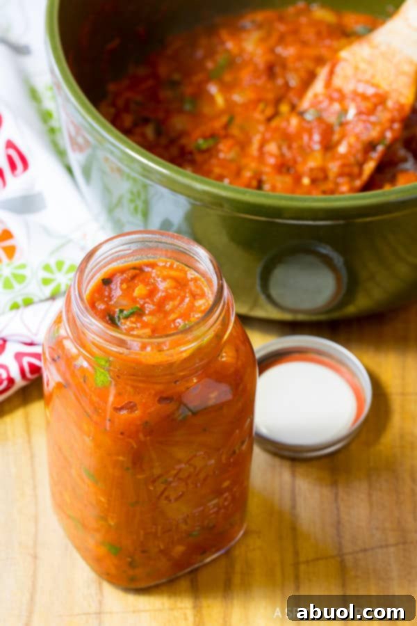 A pristine glass mason jar filled with freshly made homemade marinara sauce, showcasing its rich, deep red color.