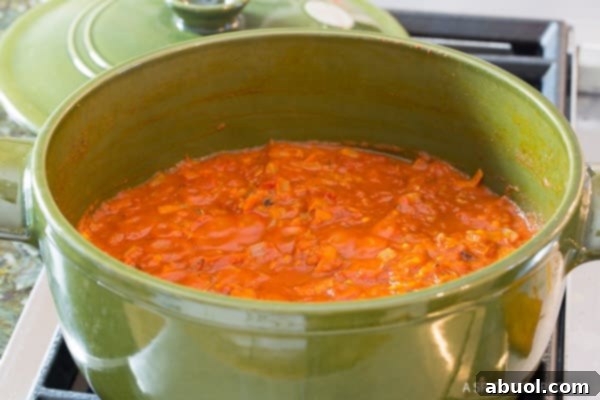 A close-up view of vibrant tomato sauce simmering gently in a green cooking pot, steam rising.