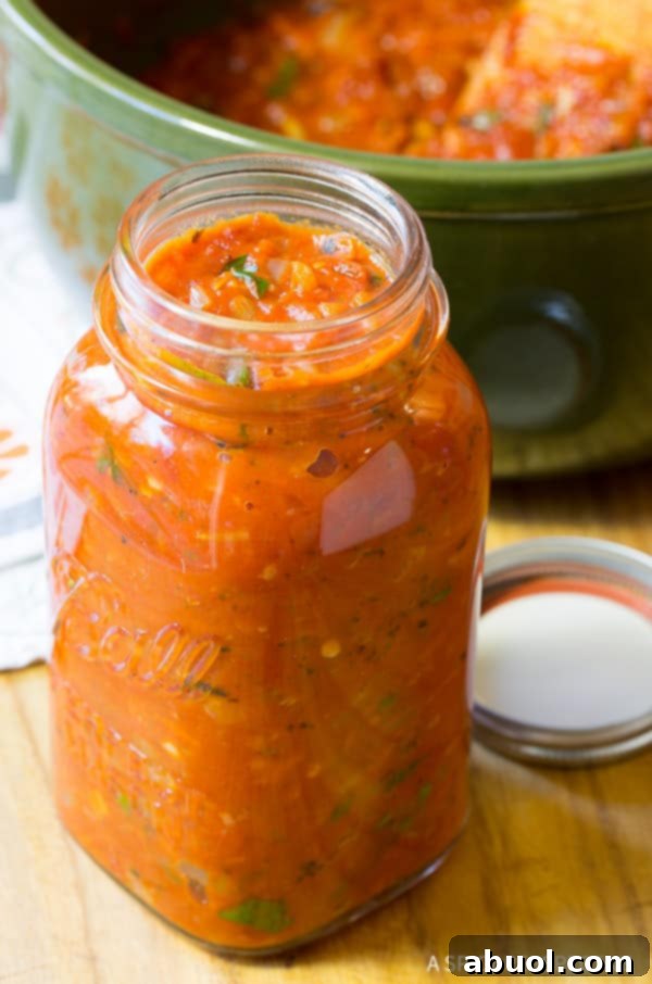 A charming mason jar brimming with zesty homemade marinara tomato sauce, set against a rustic background.
