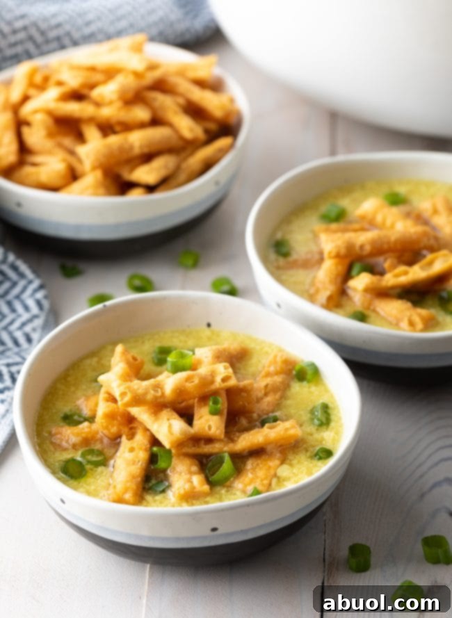 Two steaming bowls of homemade egg drop soup, garnished with vibrant green onions and crispy fried wonton strips, ready to be enjoyed.