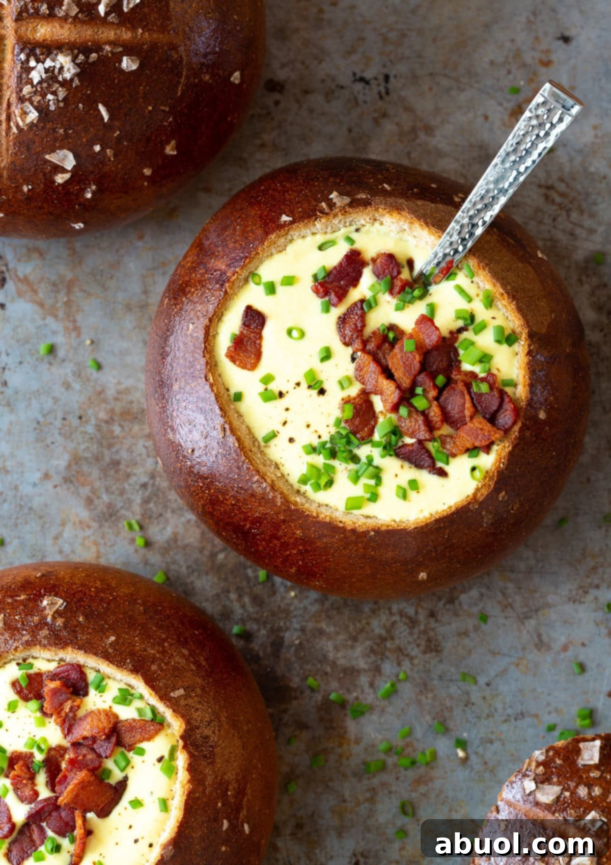 Overhead shot of a rustic bread bowl brimming with creamy Irish Beer Cheese Soup, topped with crispy bacon bits. 