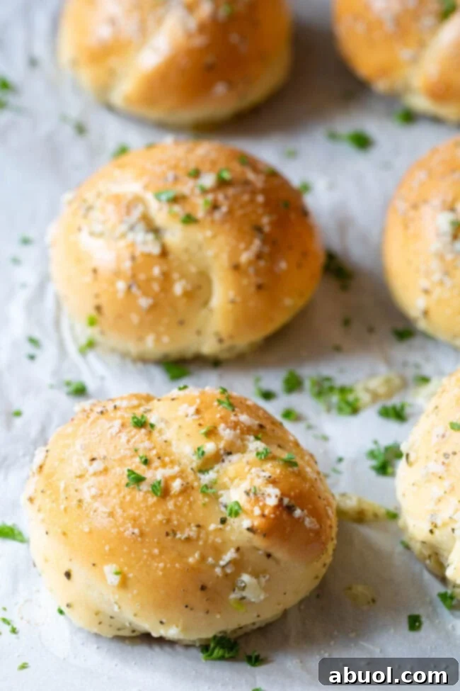 Unbaked garlic knots neatly lined up on a baking sheet lined with parchment paper, ready for their quick rise and bake.