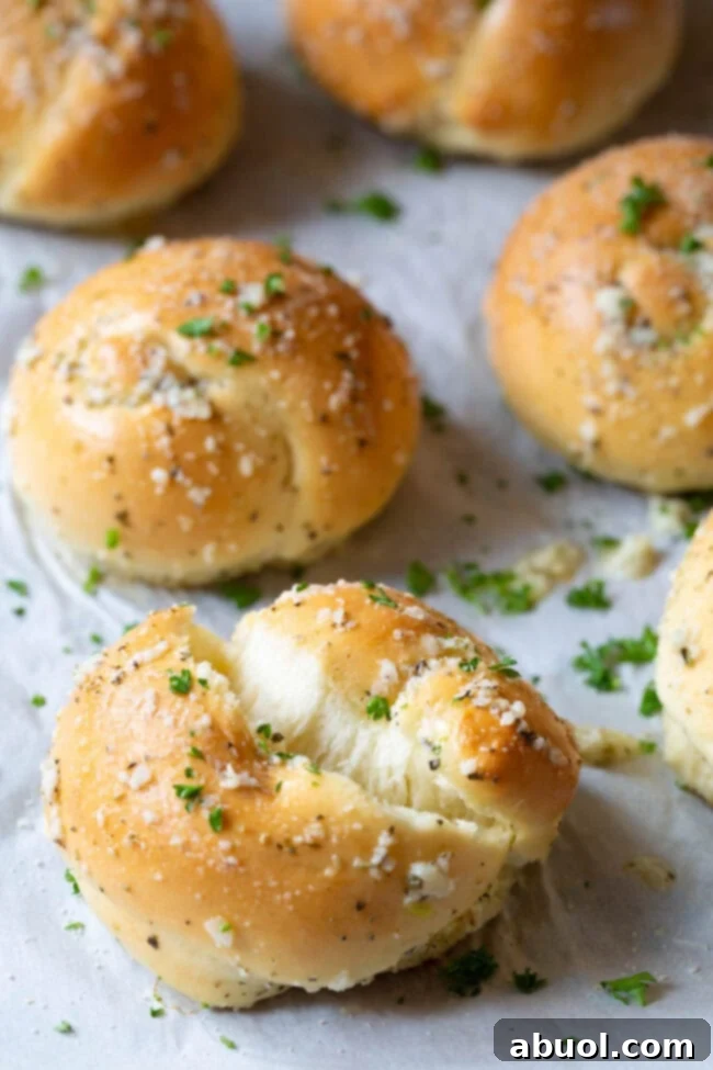 A freshly baked garlic knot ripped in half, revealing its airy, fluffy interior and soft texture.