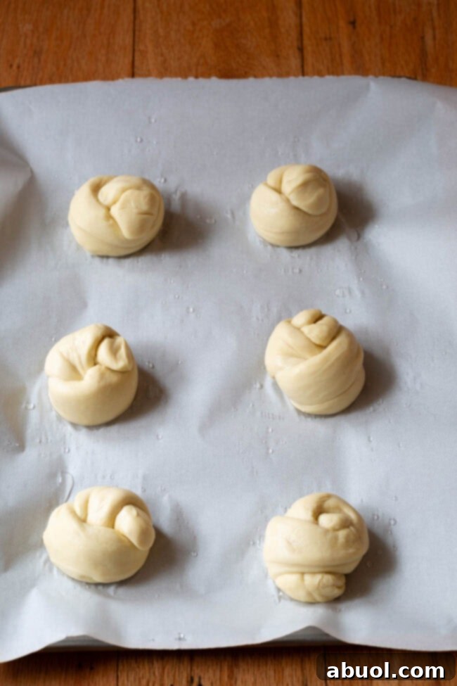 Garlic knots on a baking sheet before being baked, showing their risen, plump form.