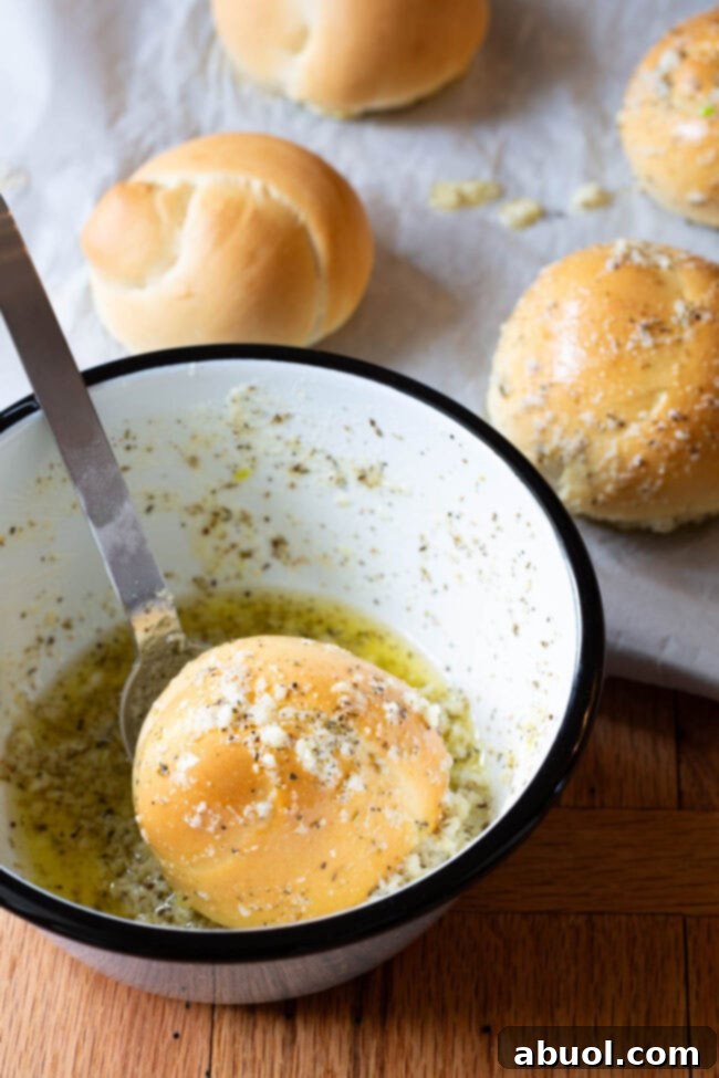 A baked garlic knot being dunked into a bowl of melted garlic butter, ensuring every crevice is coated in flavor.