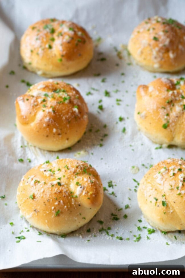 Baked and buttered garlic knots perfectly lined up on a baking sheet, ready to be served.
