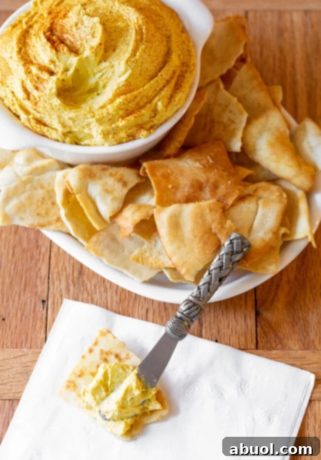 Spreadable cheese in a bowl next to homemade pita chips.