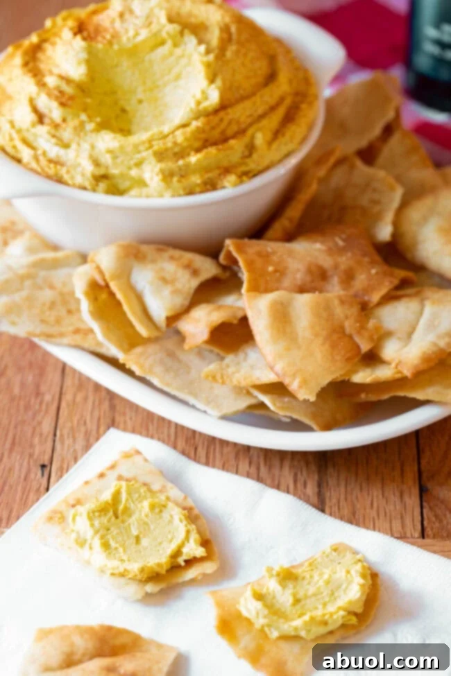beer cheese dip in a small bowl next to a plate of pita chips.