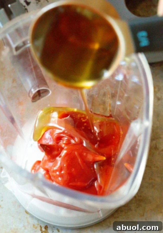 Close-up shot of Catalina dressing ingredients, including ketchup, vinegar, and honey, in the bottom of a blender pitcher.