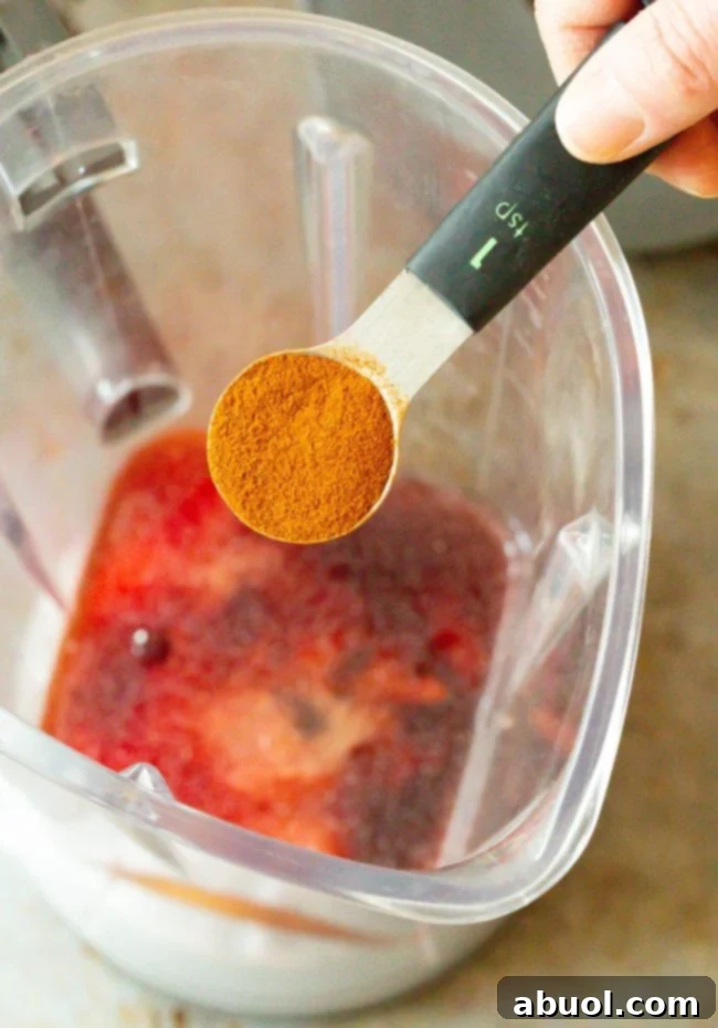 A teaspoon with smoked paprika held over a blender, ready to be added to the Catalina dressing ingredients.