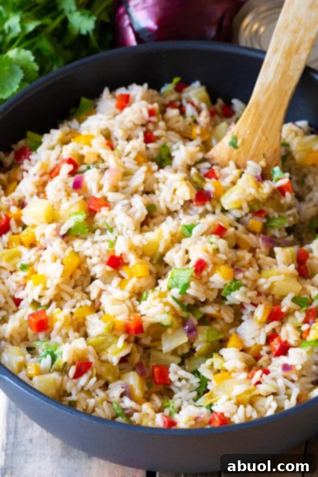 Fluffy cooked rice being gently folded into the colorful vegetable mixture.
