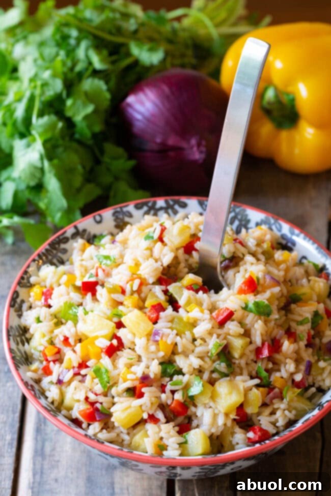 Delicious Zesty Caribbean Confetti Rice served in a white bowl with a large serving spoon.